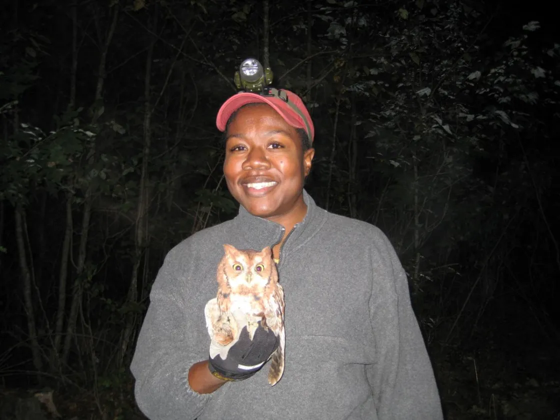 Dr. Camille Hopkins at night with headlamp holding an owl
